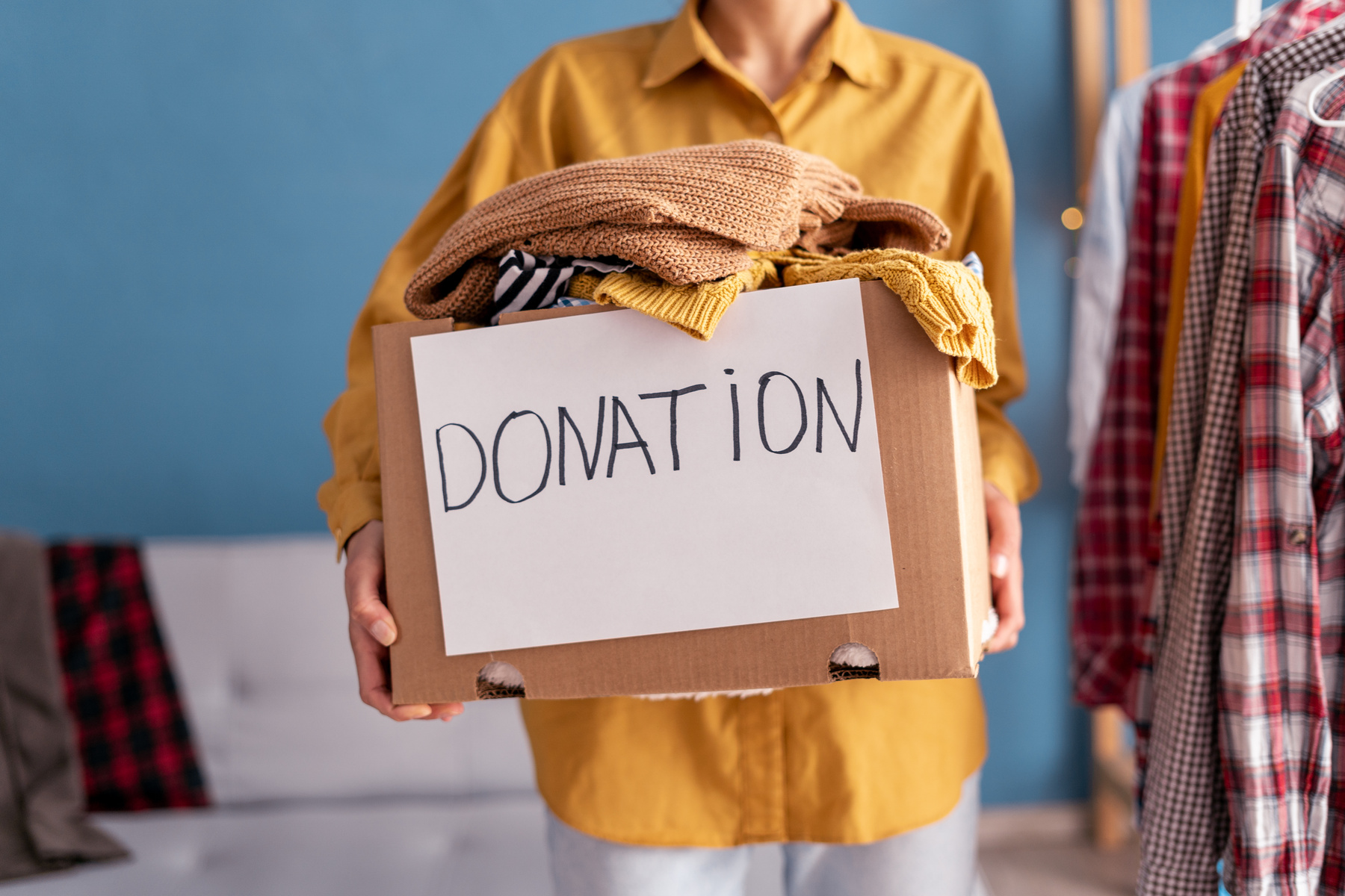 Donation concept. Woman holding Donation box with donation clothes in her home. Charity. Helping poor people.