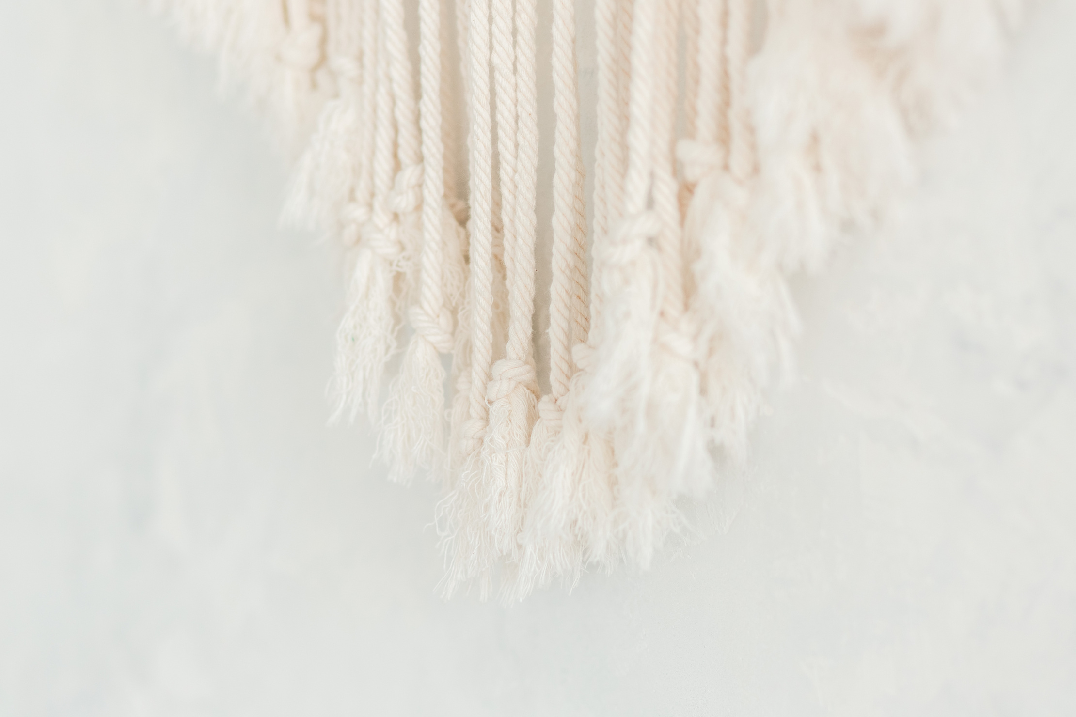 Close up of cotton macrame panel fringe in a minimalistic scandinavian wall. Texture. Background.